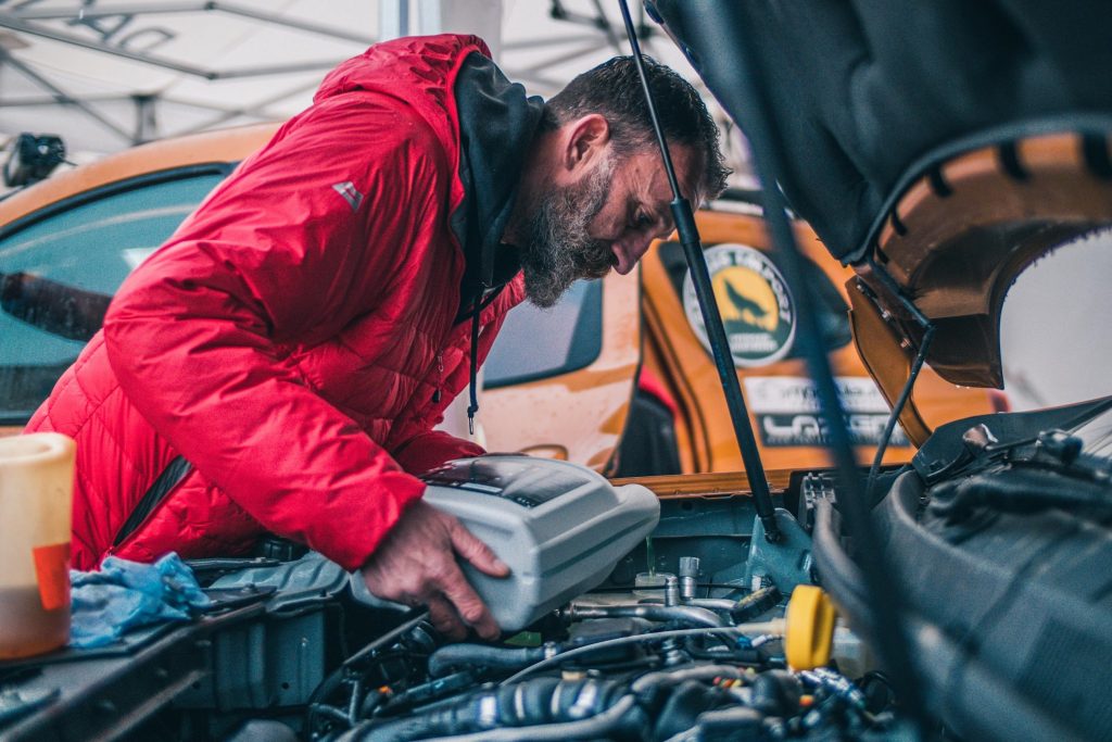 image showing man topping up motor oil level in an engine