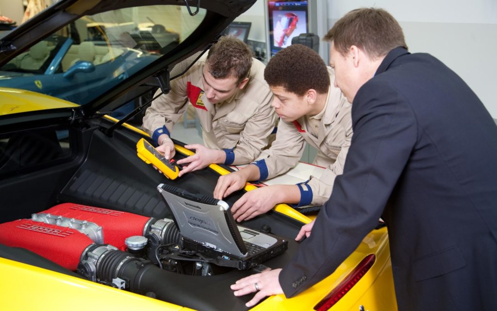 technicians and trainer using diagnostics to examine a ferrari engine 