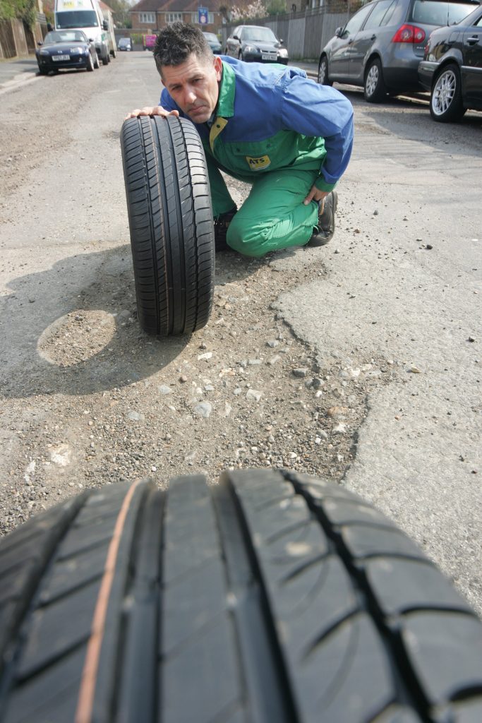 image of technician looking at a tyre to gauge how worn it is