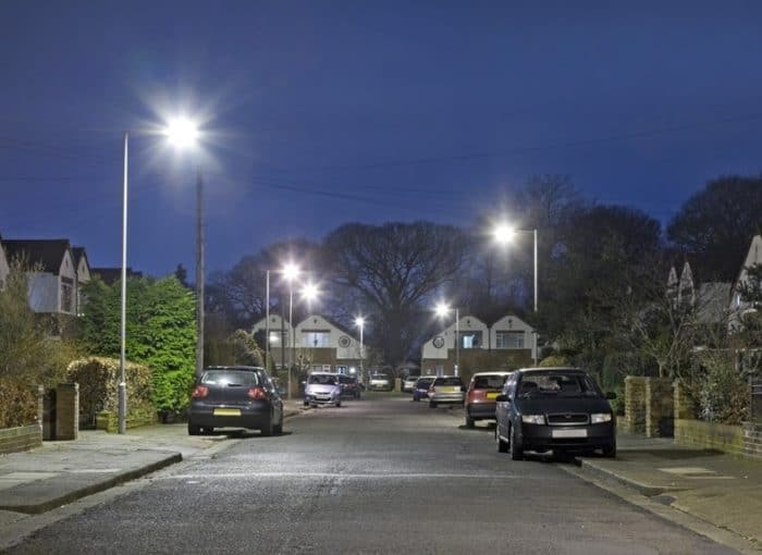 image showing a uk street at night with cars parked on the kerb, showing dropped kerbs and driveways