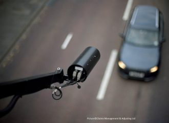 request cctv footage camera mounted over an English main road. Focus on the camera only with car blurred