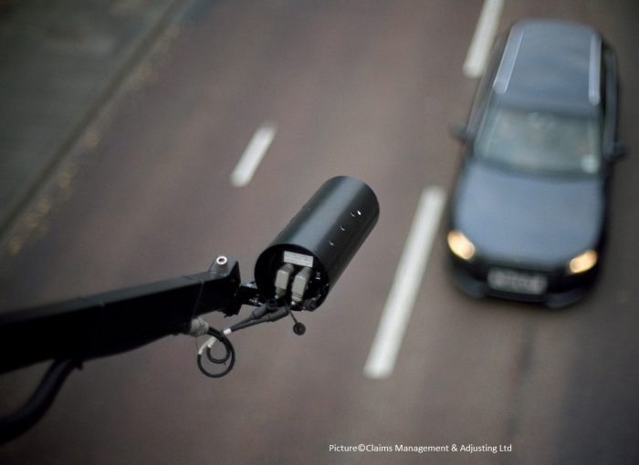 CCTV mounted over an English main road. Focus on the camera only with car blurred